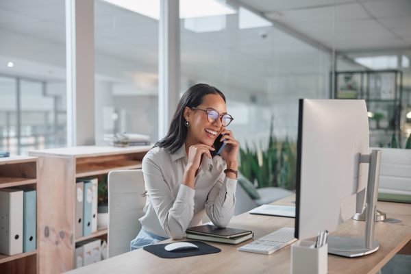 Phone call, business and woman with a computer, conversation and smile with project and talking. Person, office and employee with pc and worker with joy and laughing with communication and discussion